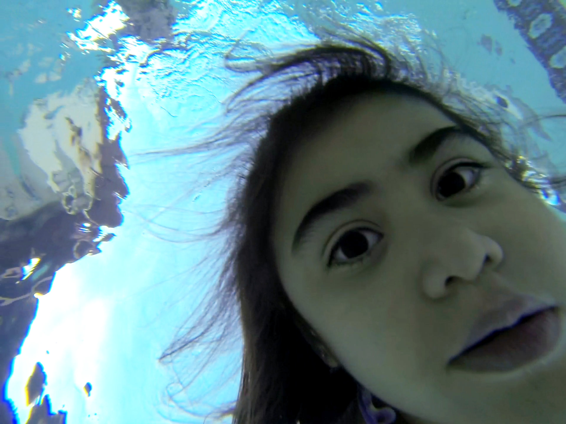 Chanielle Islas underwater in my backyard swimming pool looking down at a GoPro Hero3 camera in her hand.