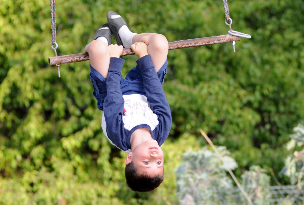 Danny Perez hanging upside down from a swing